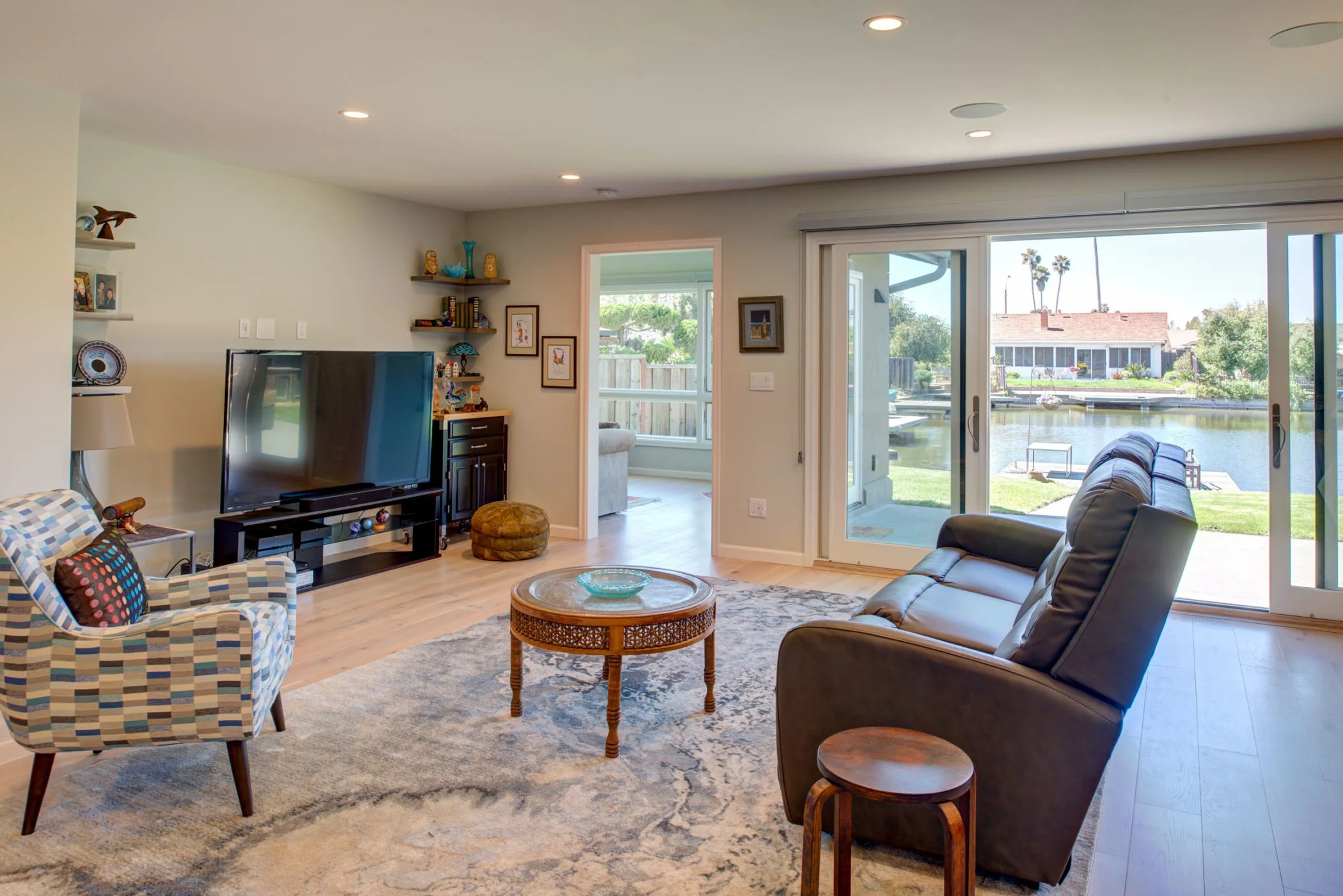 Living room with sliding glass doors opening to the waterfront yard, allowing natural light and views while maintaining an open layout for daily living.