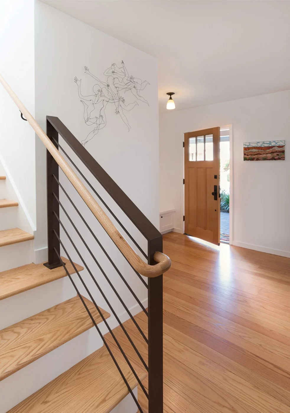 Entry and stairway with wood steps, modern metal railing, and natural light from open front door