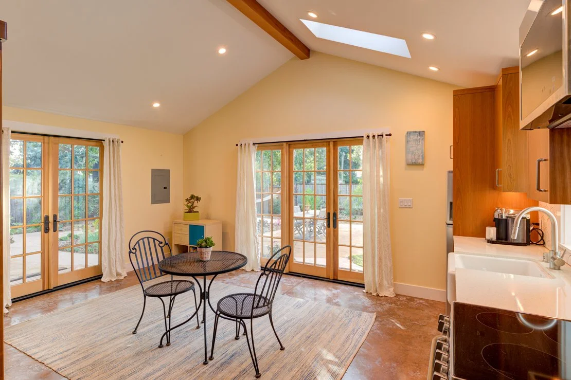 ADU interior with vaulted ceiling, skylights, French doors on two sides, living/ding area and Kitchen along one wall