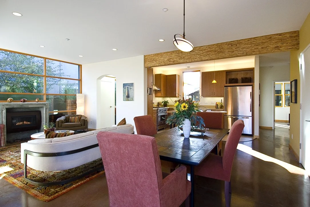 Open concept living and dining area with fireplace, large windows, and warm wood finishes that emphasize natural light, energy efficient design, and seamless flow between shared living spaces.
