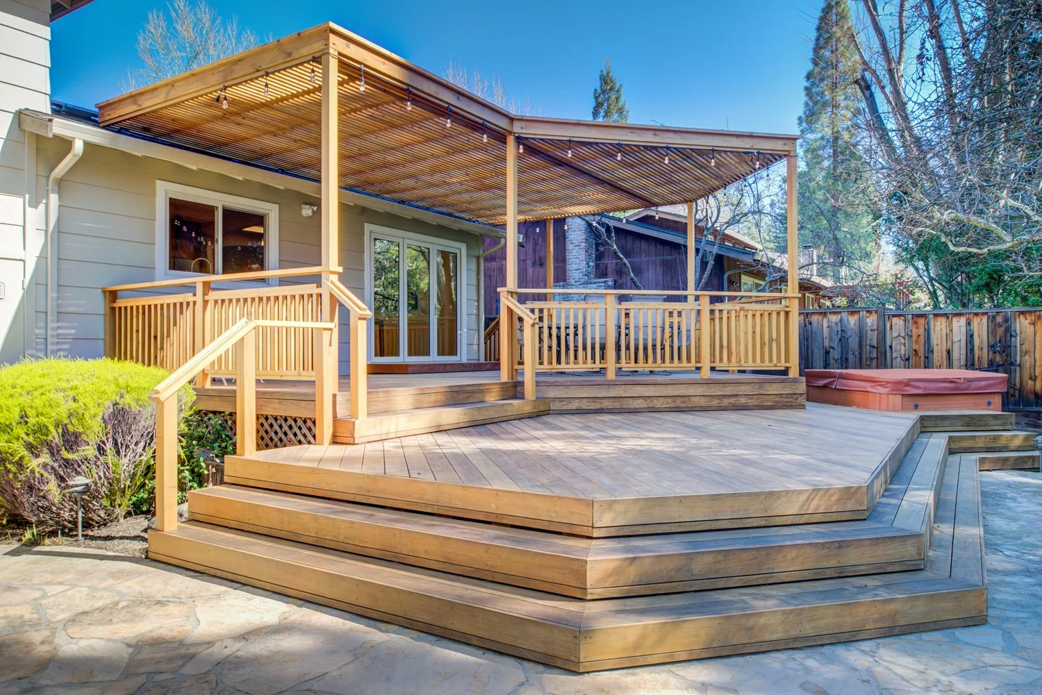 Rebuilt timber pergola and stepped wood deck stage outdoor living adjacent to the kitchen-dining core, enhancing indoor-outdoor flow.