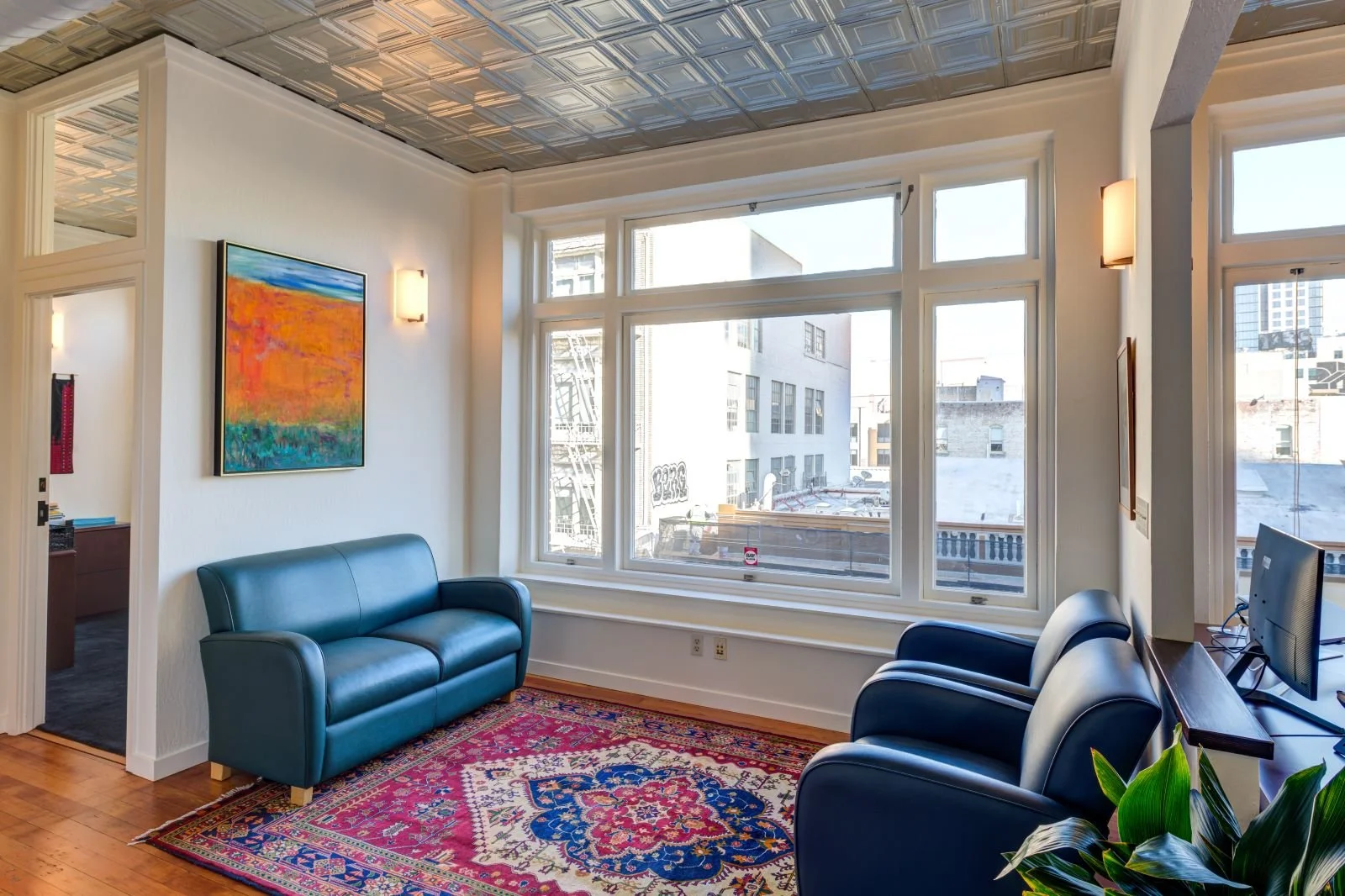 Waiting area with large windows looking over downtown Oakland. Tin ceilings add character and act  as an acoustical treatment.