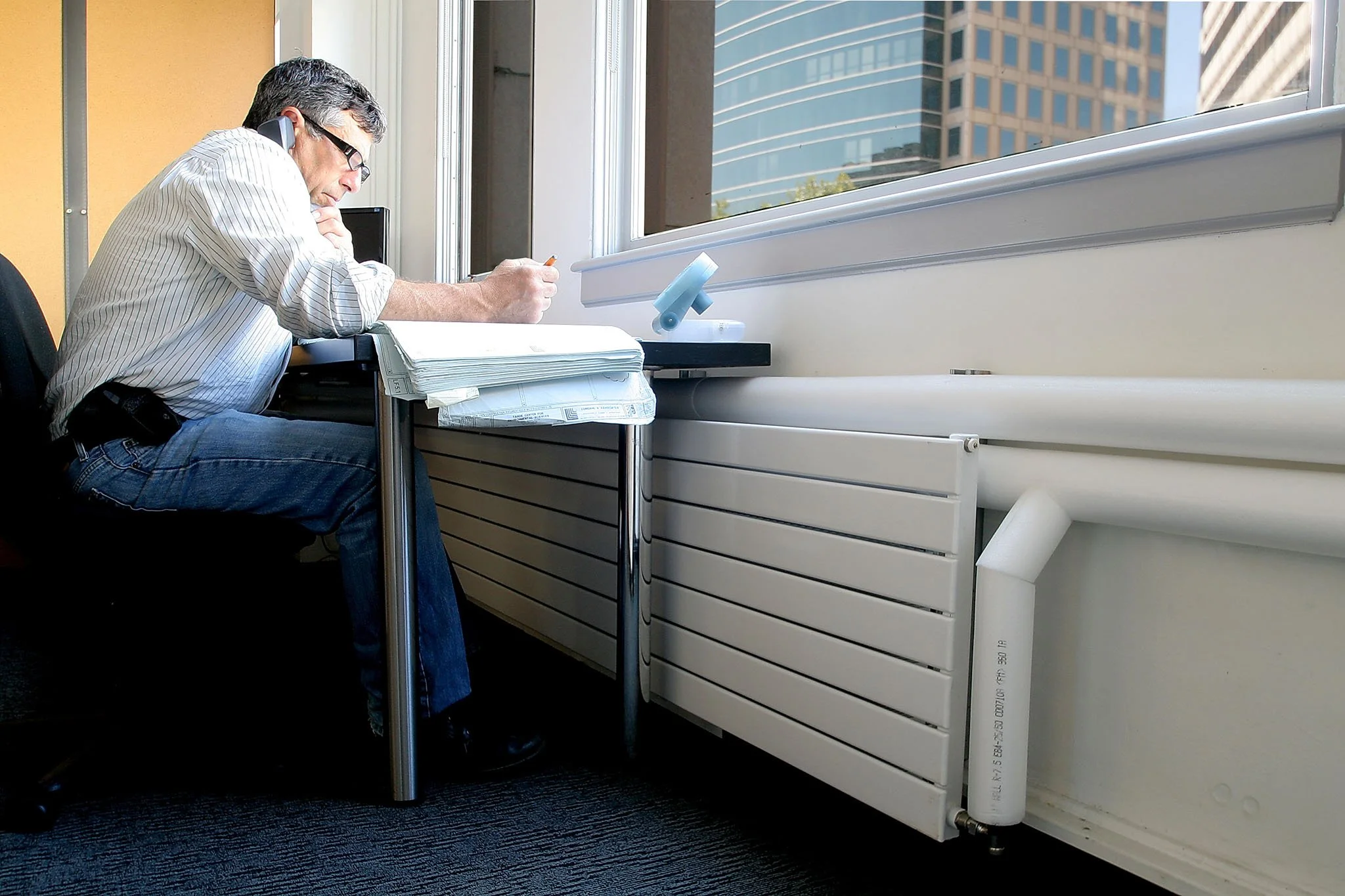 Engineer working by a large window with abundant natural light and hydronic heating along the wall, illustrating the daylit LEED Platinum tenant improvement in downtown Oakland.