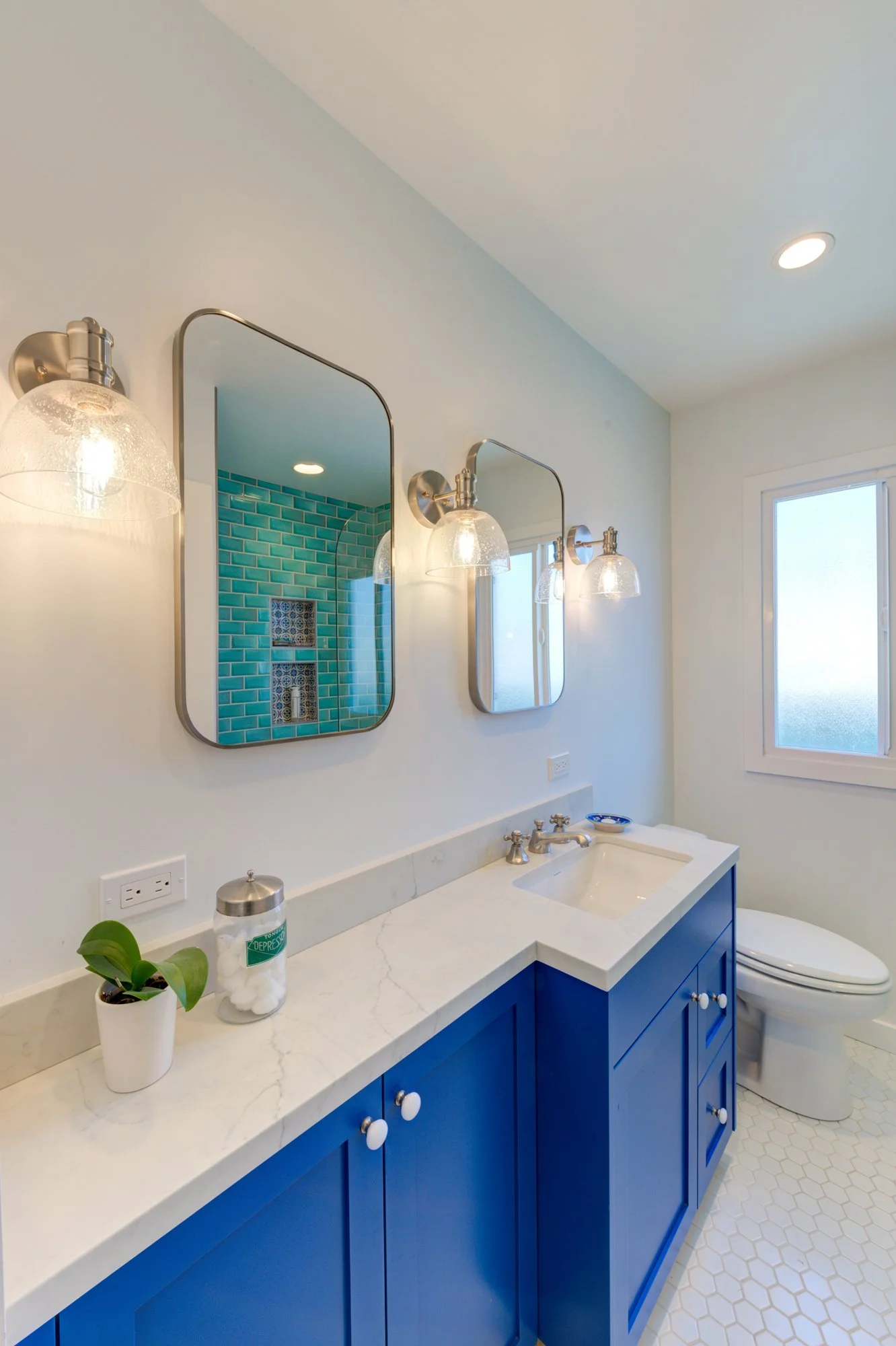 Bathroom vanity with bold blue cabinetry, white quartz countertop, and dual mirrors, reflecting the colorful design approach used throughout this second-story addition and remodel.