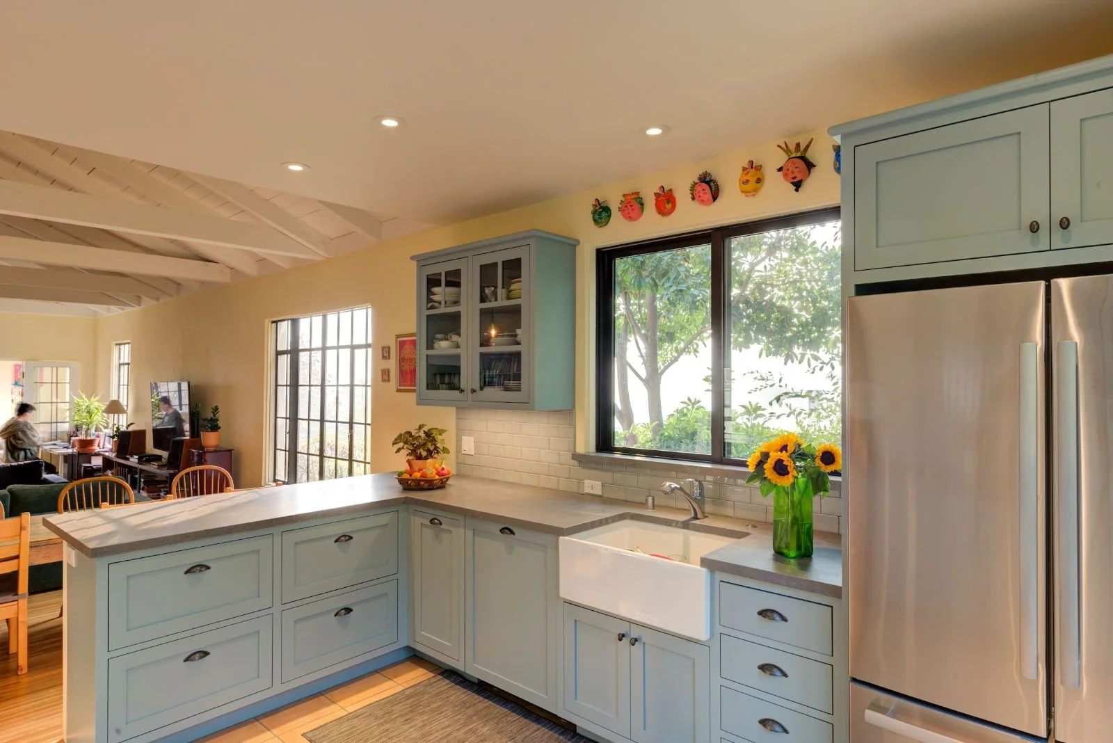 Soft blue Levitch built cabinets showcasing the connection to the Dining and Living Rooms. Storage is a mixture of cabinets (some with glass fronts), drawers and floating shelves.