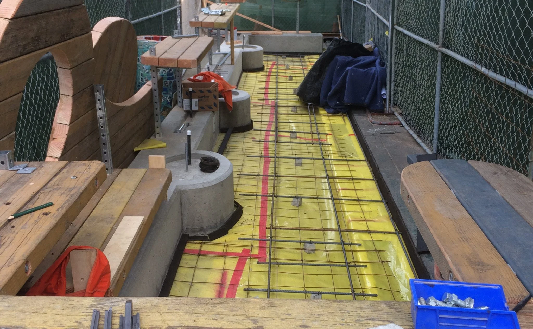 Construction phase showing workers installing concrete base and support structure for the new parklet