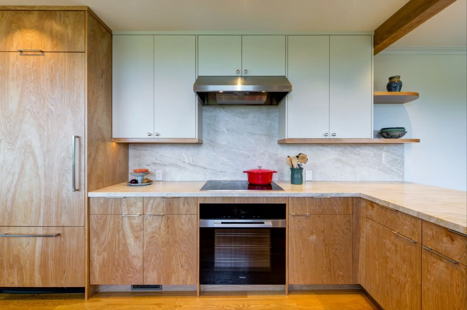 Range wall with panel-ready fridge at the left and full-height stone backsplash matching the counters