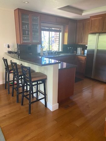 Existing kitchen before renovation showing dark wood cabinetry, older appliances, peninsula seating, and limited natural light prior to the new layout and pale finishes.