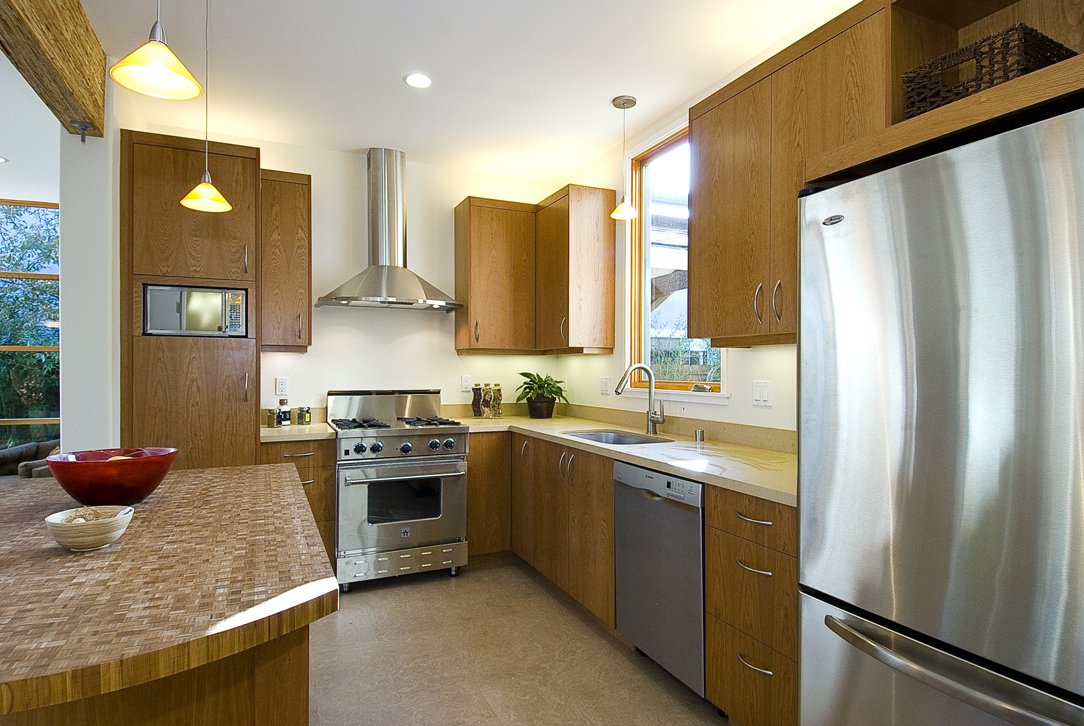 Modern kitchen with custom wood cabinets, butcher block island, stainless steel appliances, and pendant lighting designed for durability, efficiency, and everyday use.