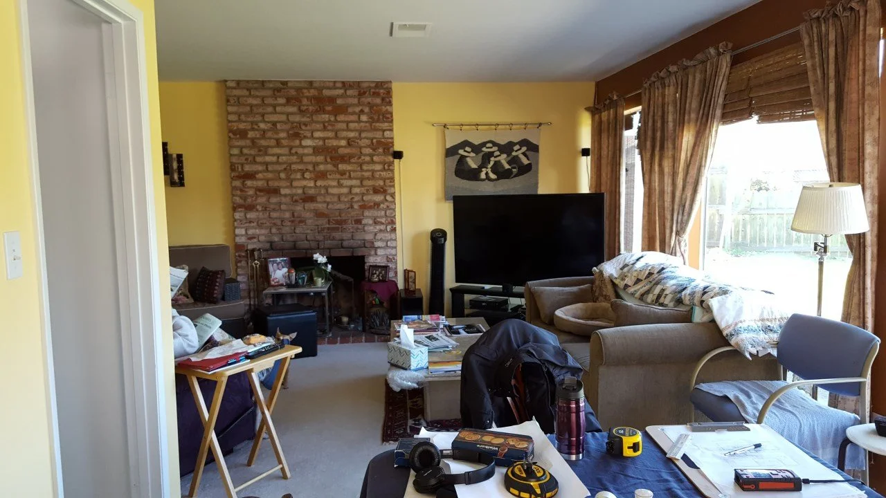 Existing living room with brick fireplace, enclosed layout, heavy furnishings, and limited daylight before the Alameda waterfront addition improved light and flow.