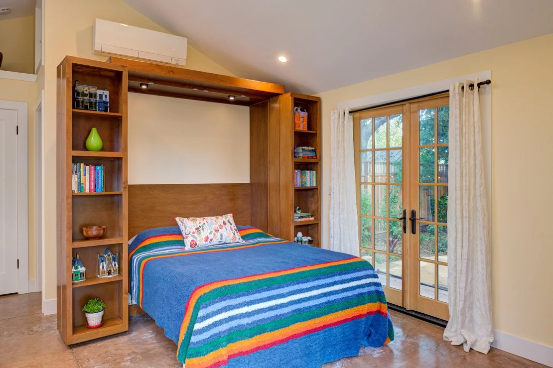 ADU Bedroom corner with Murphy bed out for sleeping. Bathroom is behind the bed, which has a nice view to the yard through more French doors.