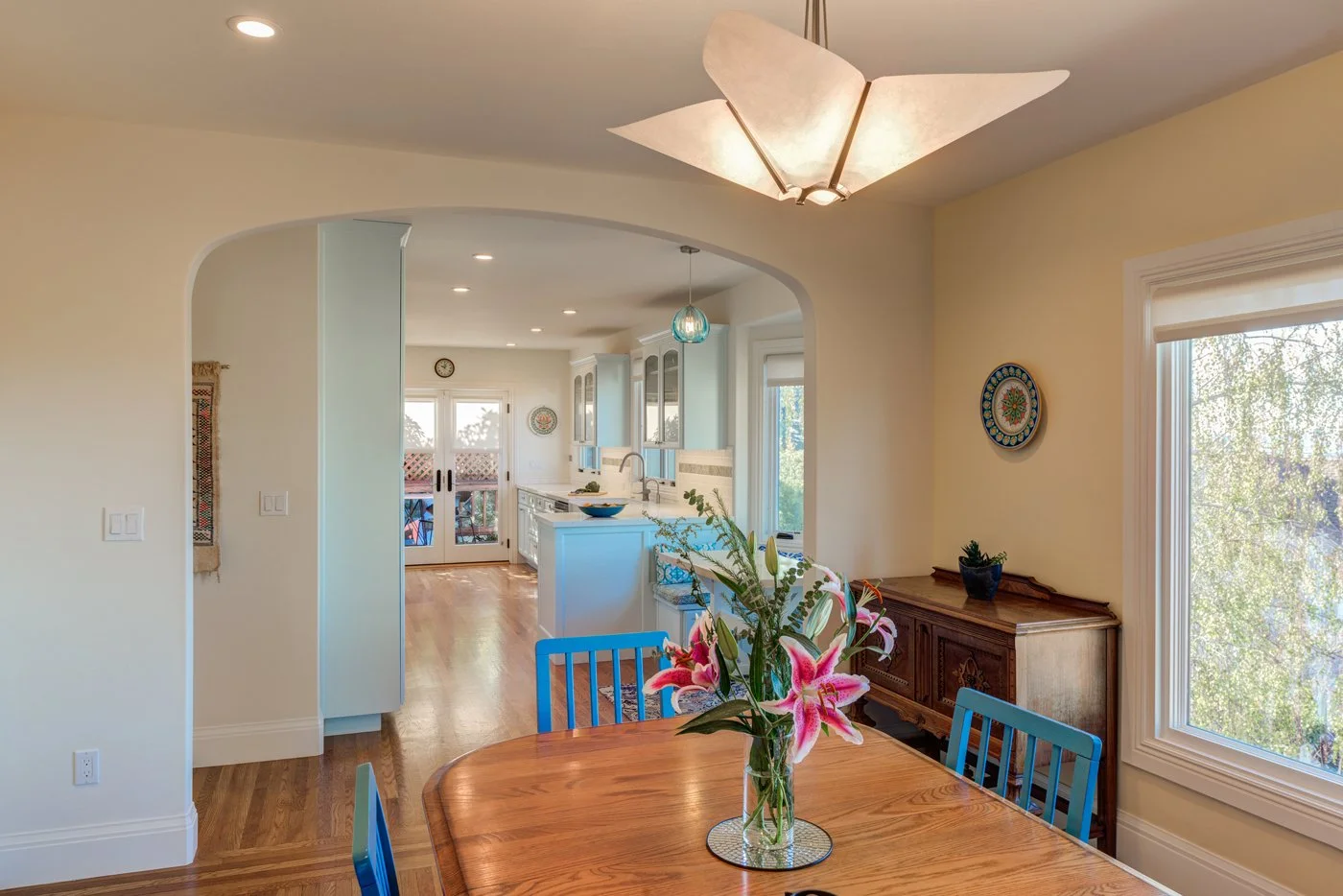 Wider opening from the dining room into the kitchen and nook, improving circulation and sightlines while highlighting the light blue cabinets and pendant lighting beyond.