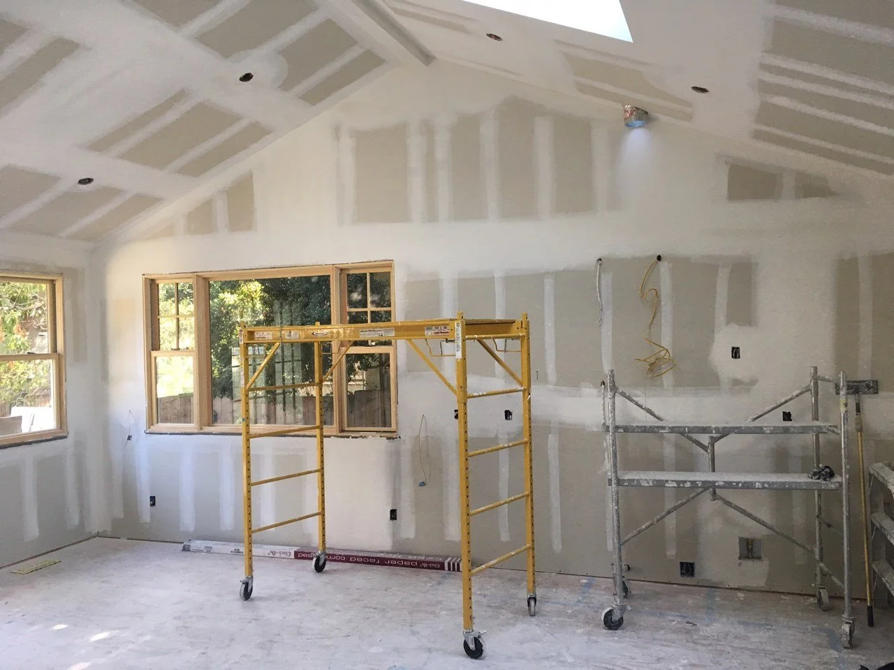 Newly drywalled kitchen and family room with vaulted ceilings and skylight openings, capturing the Lighthearted Kitchen and Family Room Addition mid construction.