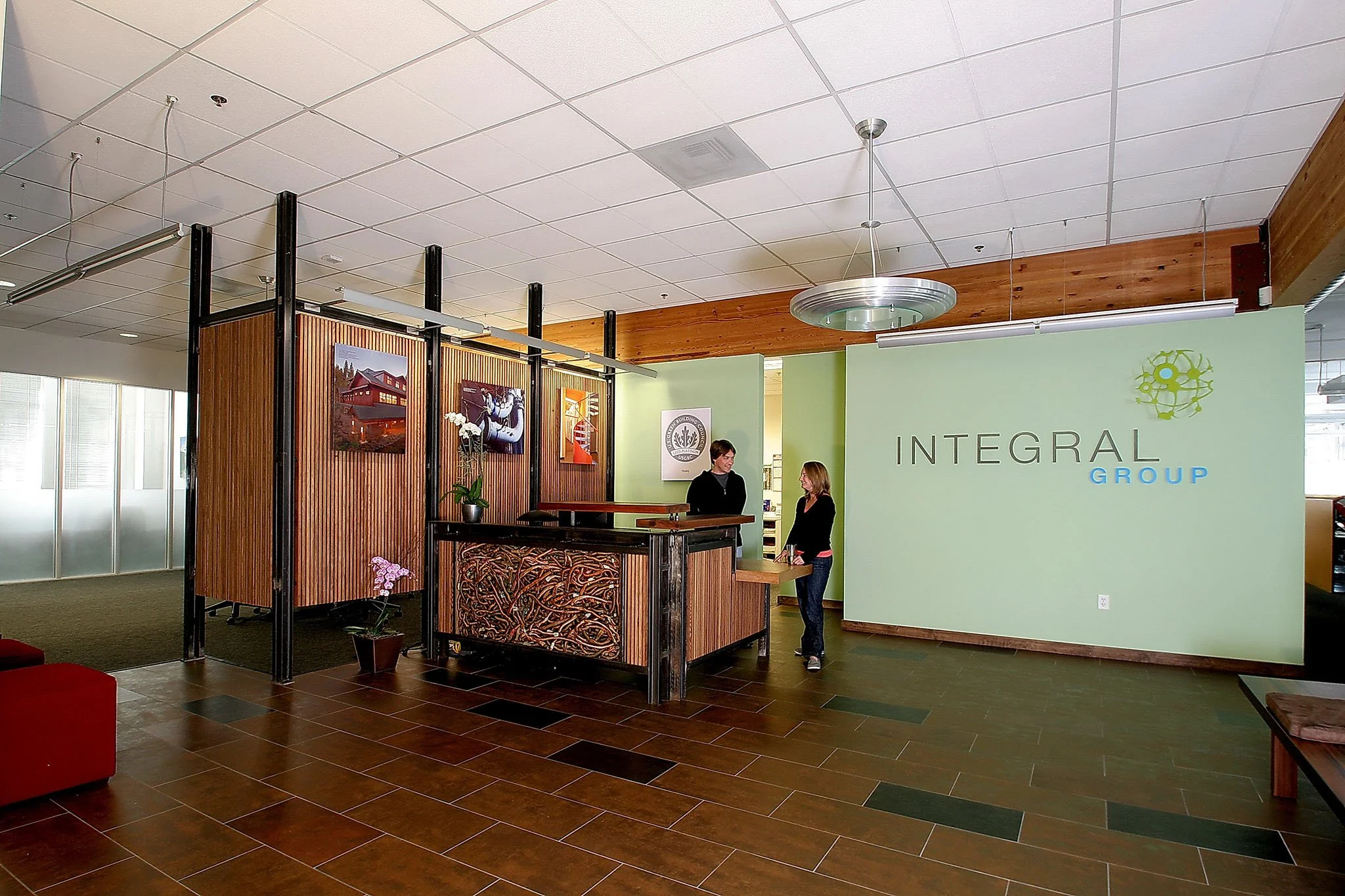 Integral Group office lobby with a custom steel and salvaged redwood reception desk, repurposed copper piping detail, and the Integral Group logo wall in Oakland.