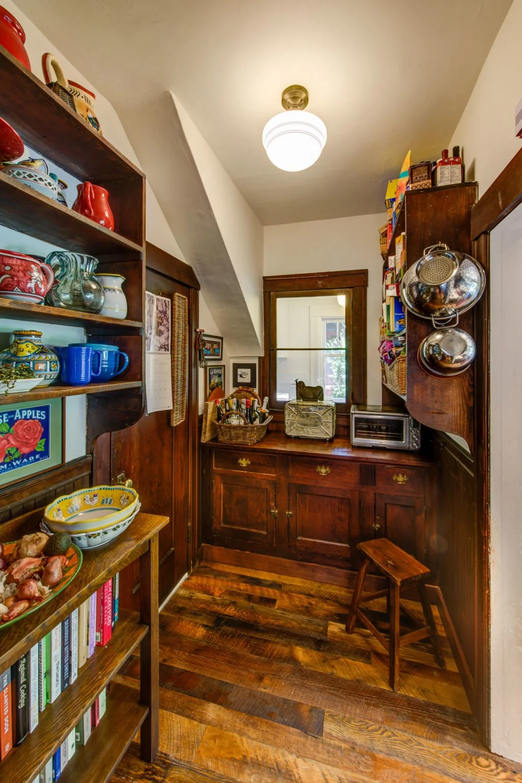 Pantry storage area with dark wood cabinetry and pull out shelves, designed to blend traditional Craftsman style with efficient modern organization near the range.