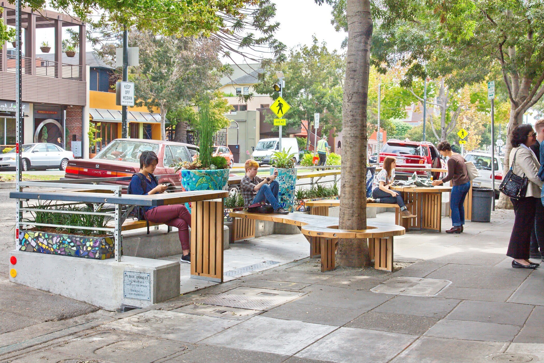 Close-up of timber bench and mosaic-tiled planter featuring salvaged bleacher wood in the parklet design