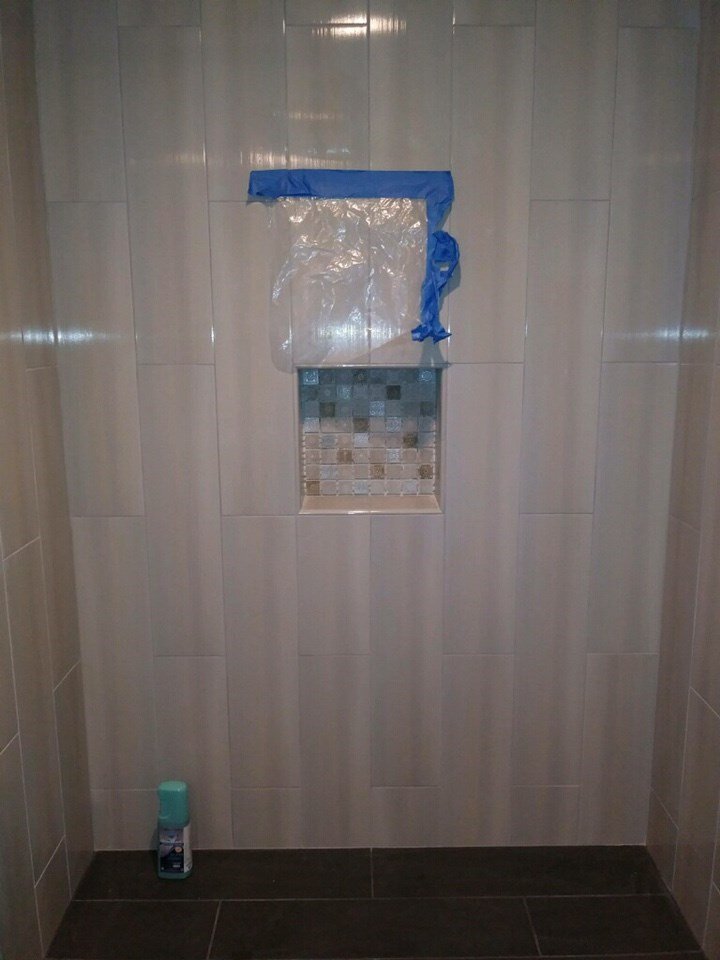 Shower remodel in progress with newly installed vertical tile and recessed niche as part of accessibility-oriented bathroom renovation.
