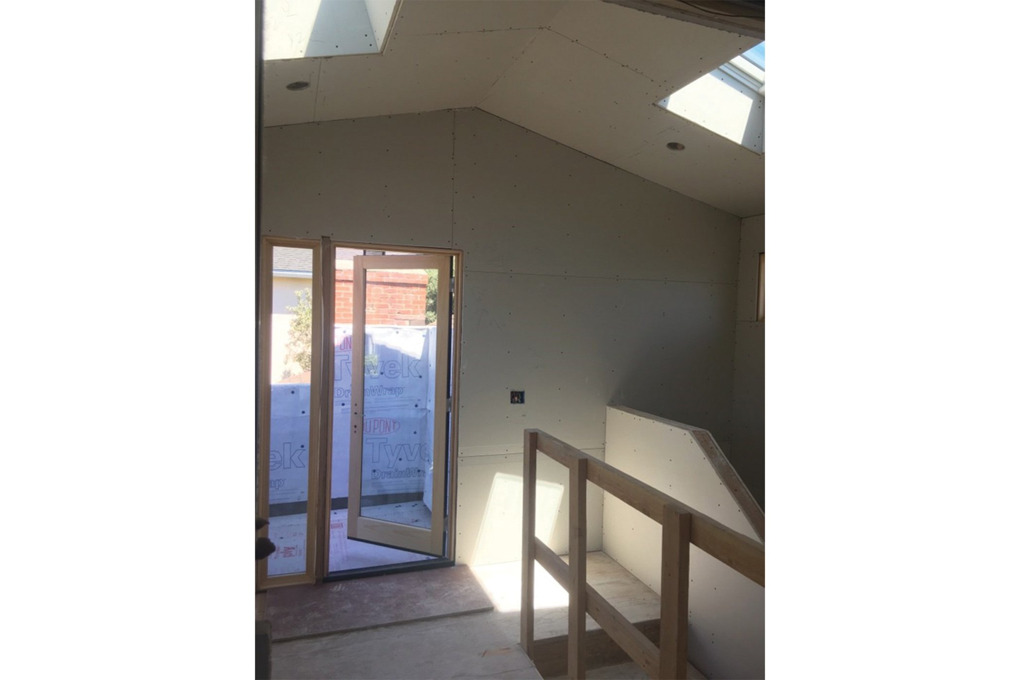 Upstairs stairwell framed and drywalled with skylights and door to new balcony