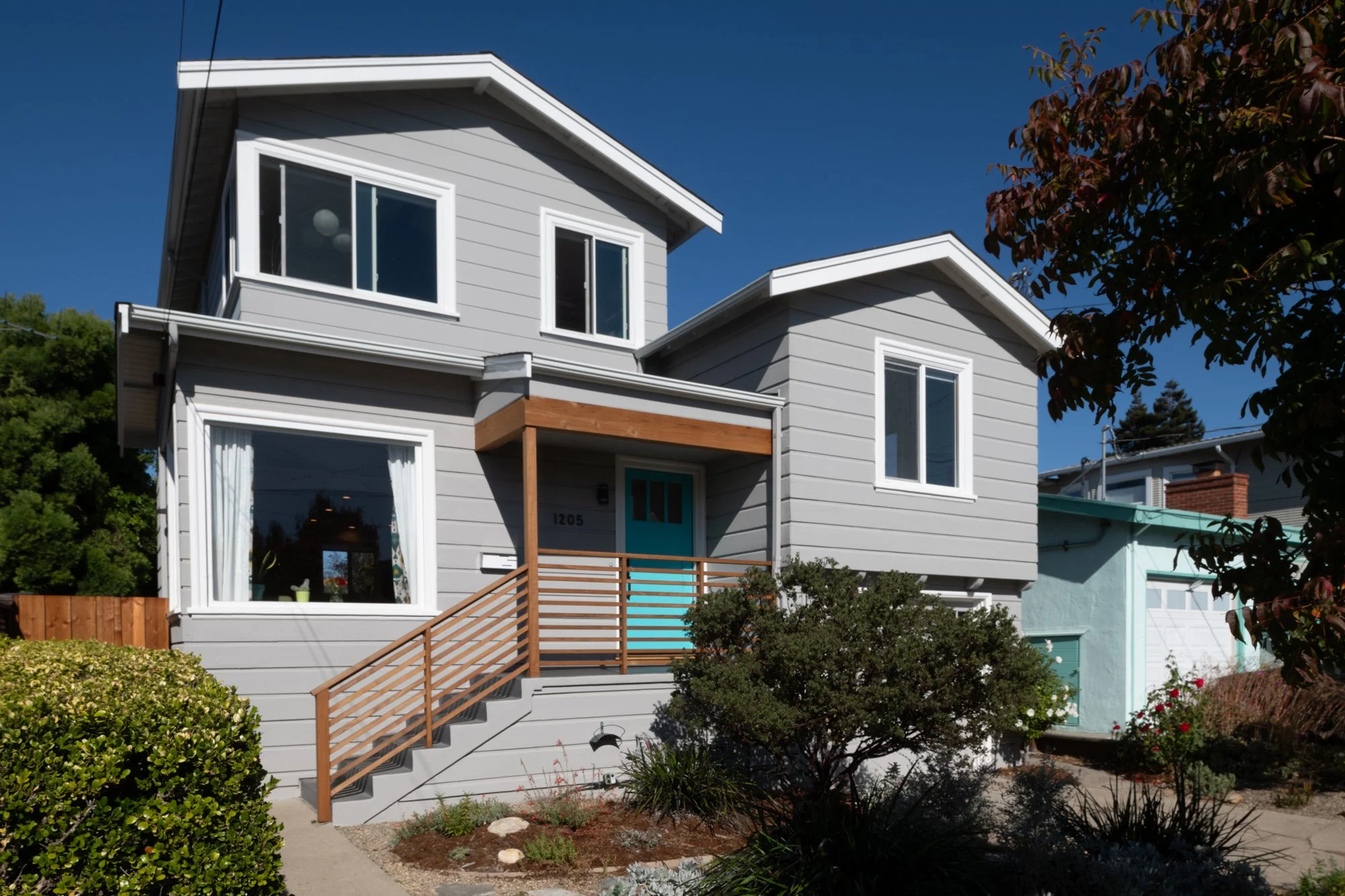 Exterior view of the completed second story addition with updated siding, modern detailing, and a new entry sequence that integrates the expansion with the original home.