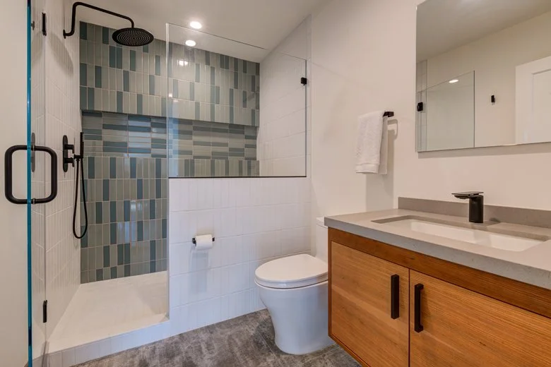 JADU bathroom with walk-in shower, mosaic tile accent wall, modern fixtures, and custom vanity, providing a comfortable and accessible space for guests or family members.
