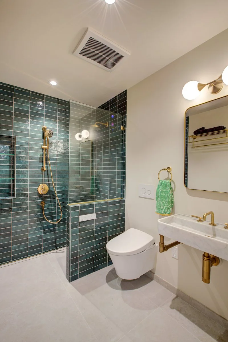 ADA compliant ADU Bathroom with a barrier-free (curbless) shower, knee space under the sink, and plenty of room to move freely. The deep sea blue and green shower tiles wrapping around the enclosure contrast the light elements of the rest of the Bath