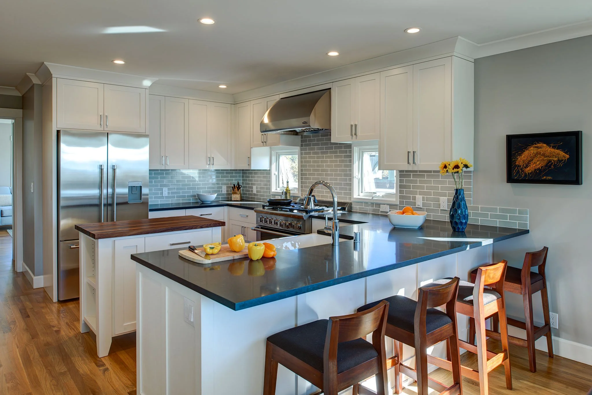 Modernized Berkeley kitchen with white shaker cabinets, gray subway tile, stainless steel range and hood, and a large island with seating. The layout boosts storage and counter space for cooking.