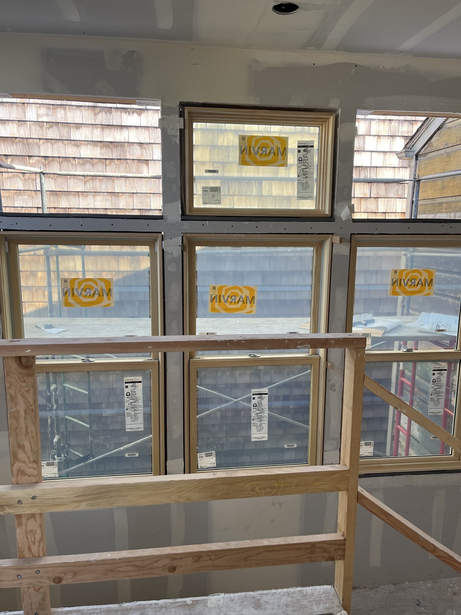 Interior view during construction showing a grid of newly installed Marvin windows and clerestory openings. The unfinished window wall brings abundant daylight into the split level addition while preserving privacy.