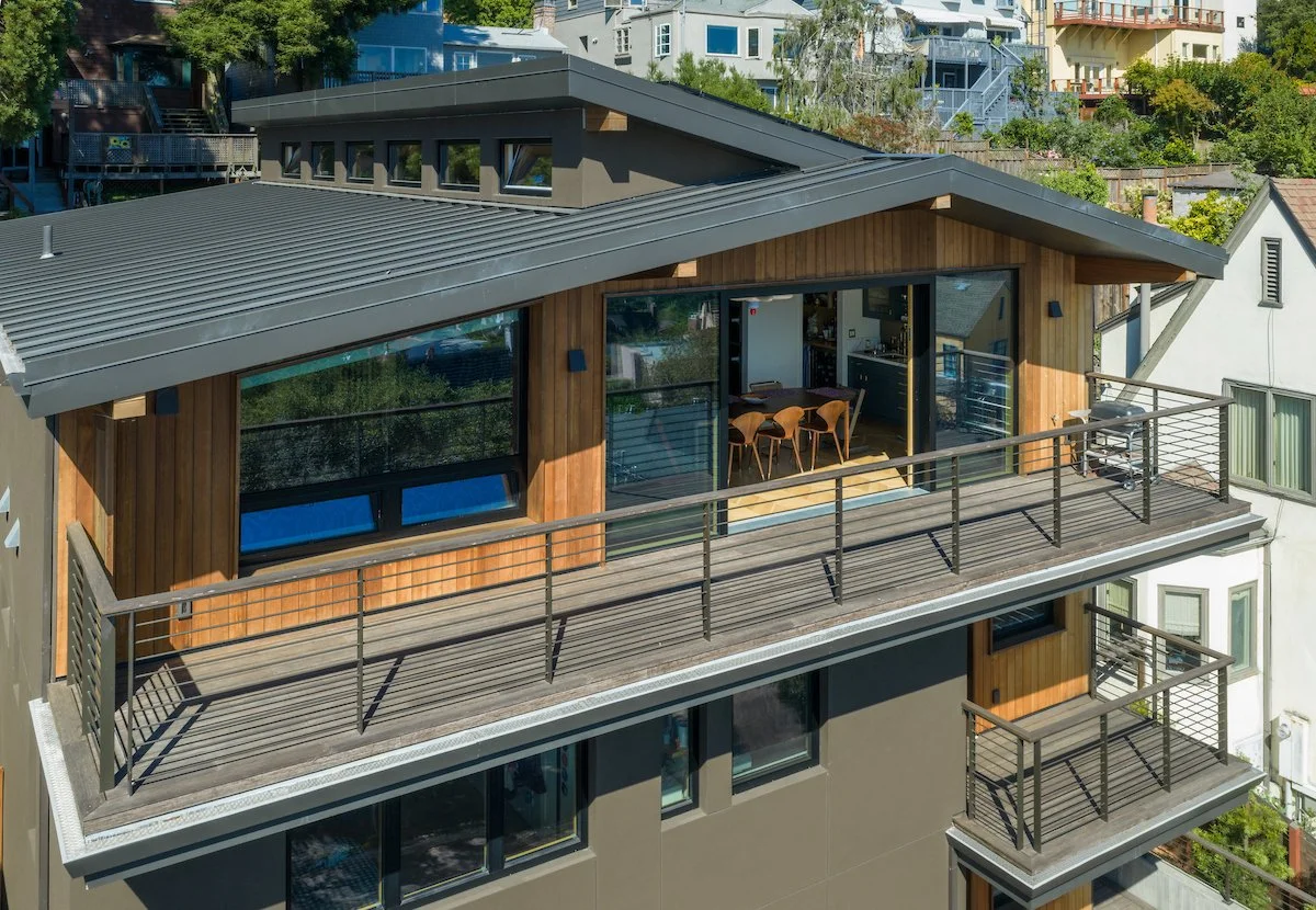 Upper front view of the home showing the metal-clad roof, clerestory windows that light the living spaces, and decks