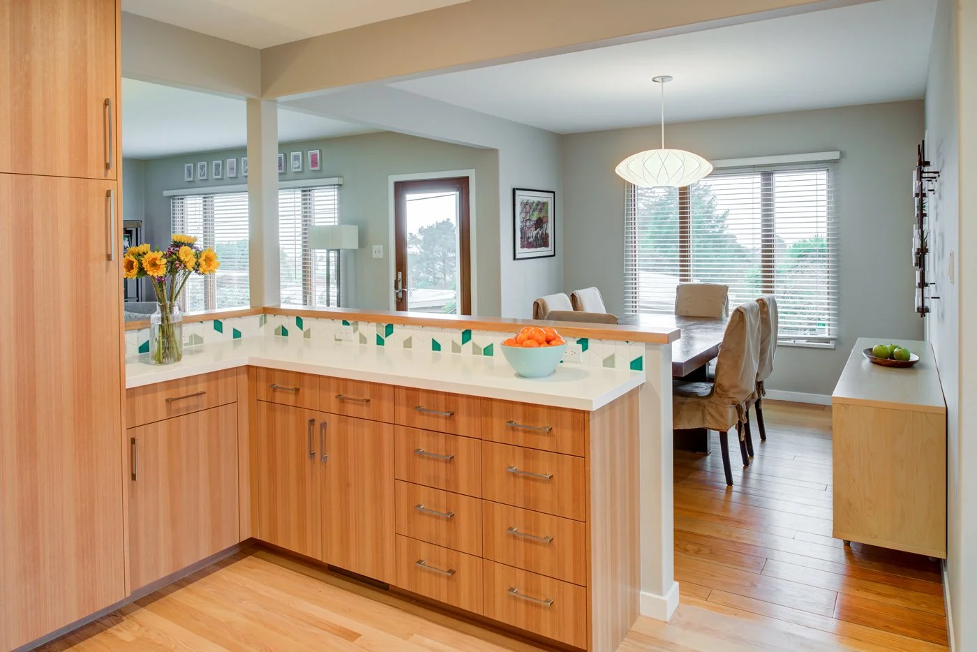 Kitchen peninsula with Levitch built eucalyptus drawers and white quartz counter, looking into the dining room after the kitchen was opened for better flow in this midcentury East Bay home.