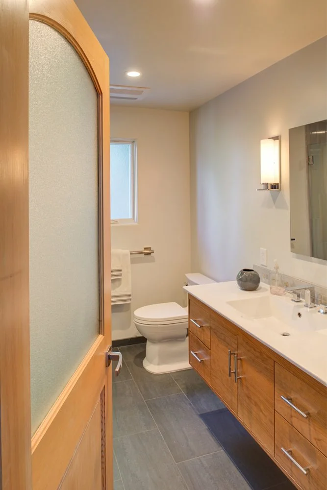 Interior of remodeled bathroom in Berkeley home, showing linen closet, privacy-glass door, and original tile.