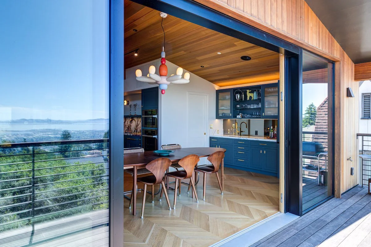 View from the upper deck toward the Dining and Bar area. The Pantry is behind the white wall at the center, and glimpses of the Bay are visible in the reflection in the panoramic doors.