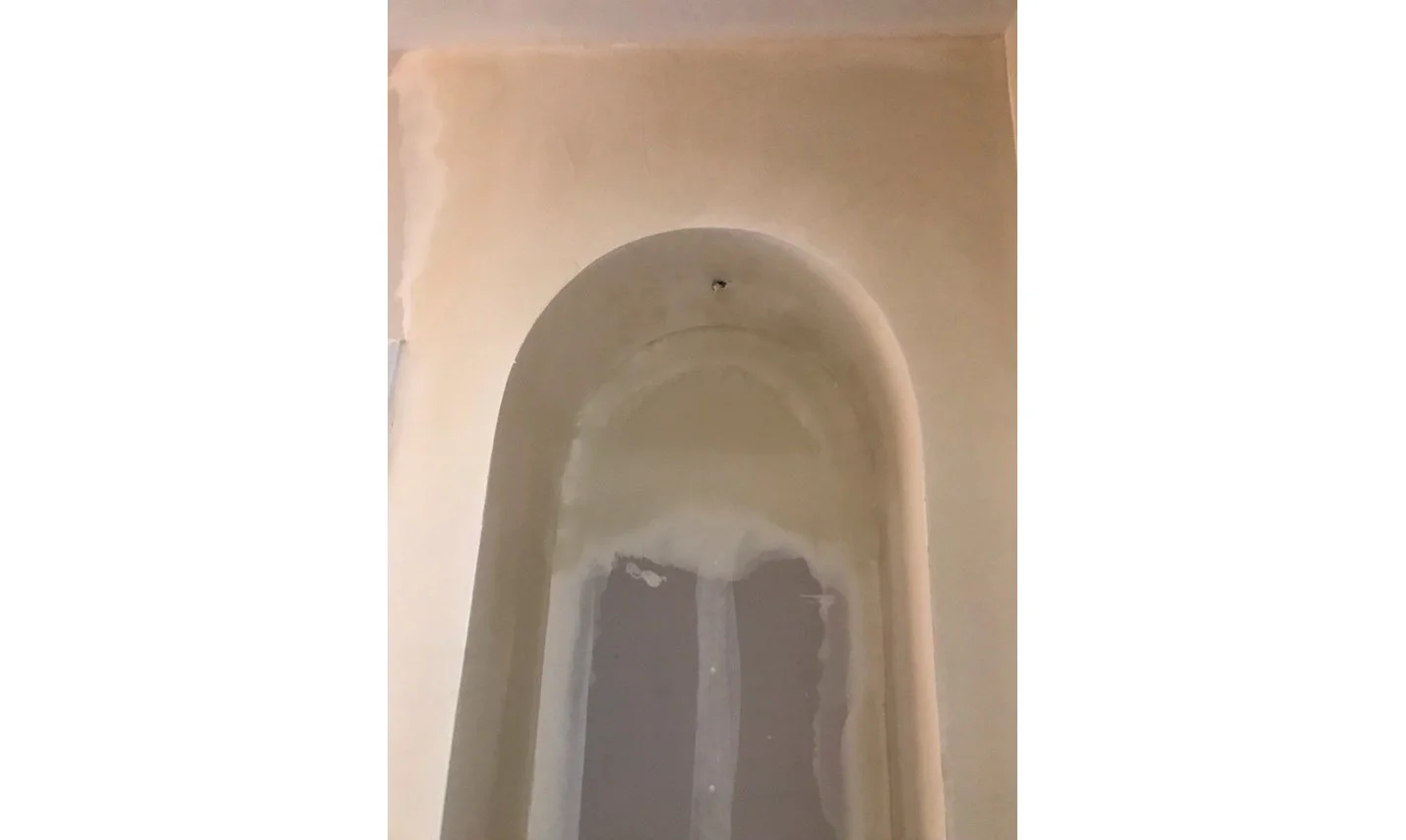 Arched wall niche under construction in the hallway, created from borrowed space during the Master Bathroom expansion.