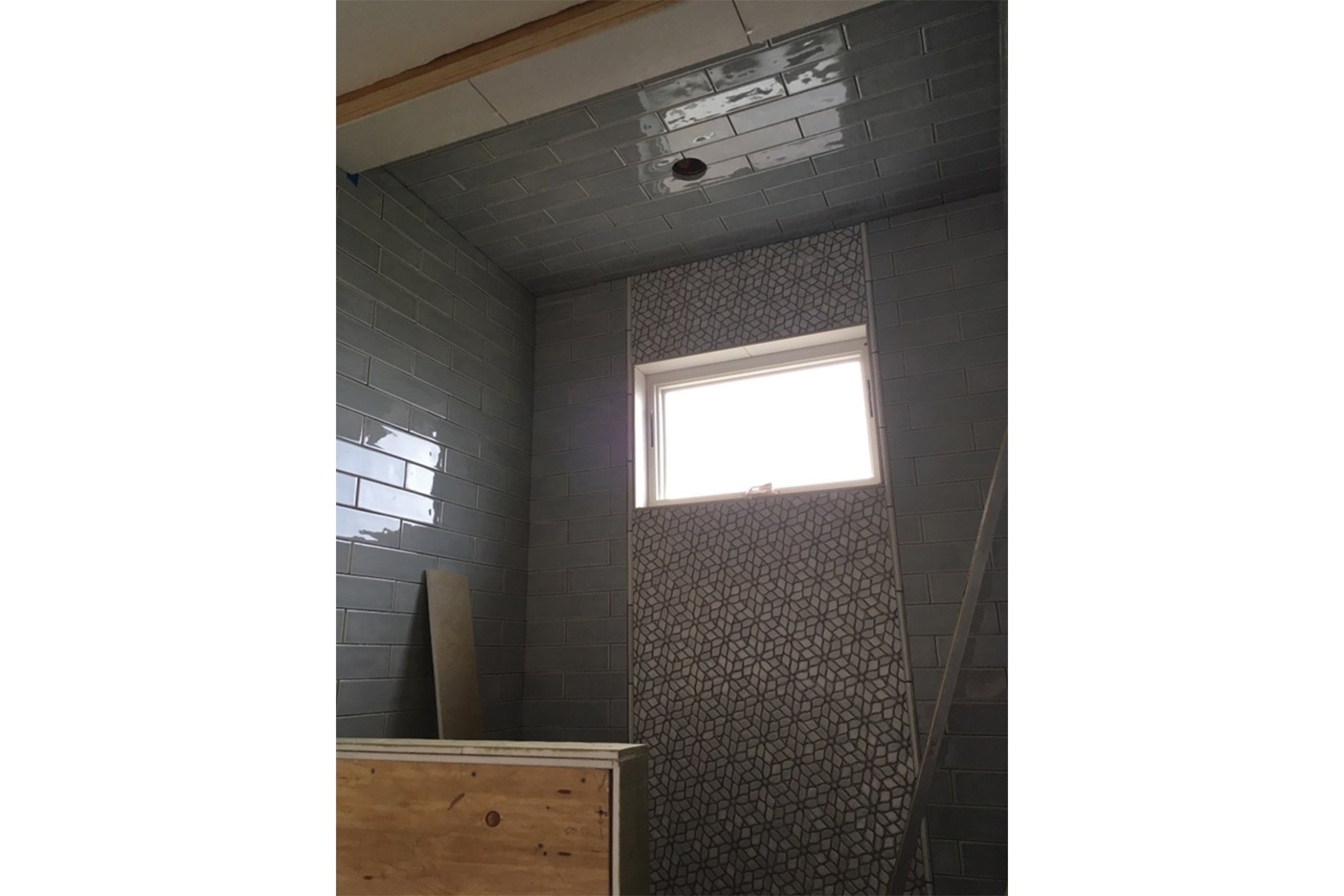 Shower tile installation with glossy subway tile and patterned accent panel