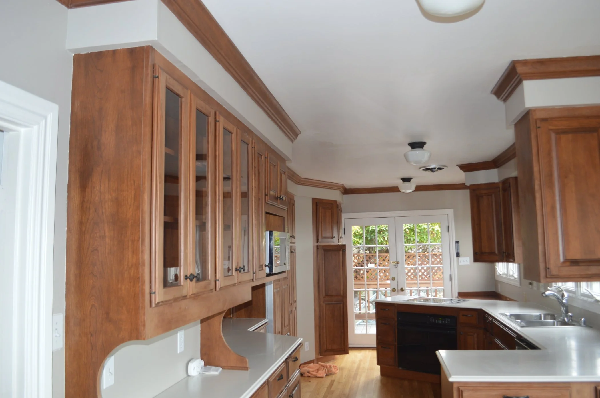 Kitchen before remodel with dark wood cabinets, angled walls, and constrained circulation to the deck, prior to Levitch straightening the wall for a more functional layout.
