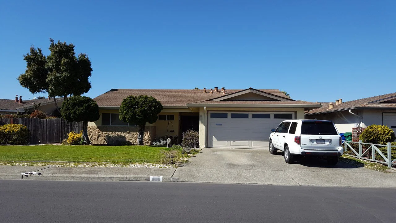 Street facing view of the original Alameda waterfront home showing dated exterior finishes and entry configuration prior to the addition and exterior updates.