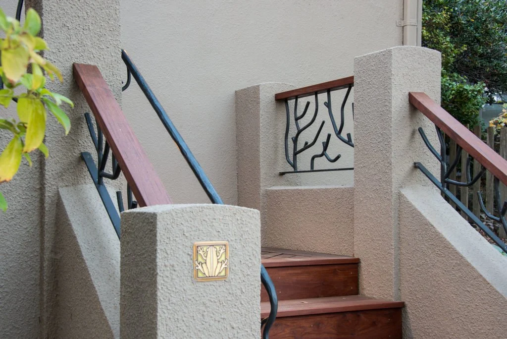 Detail of the custom metal railing with branch like forms and wood cap rails at the new entry stairs, giving the Berkeley front approach an organic look that matches the landscaping.