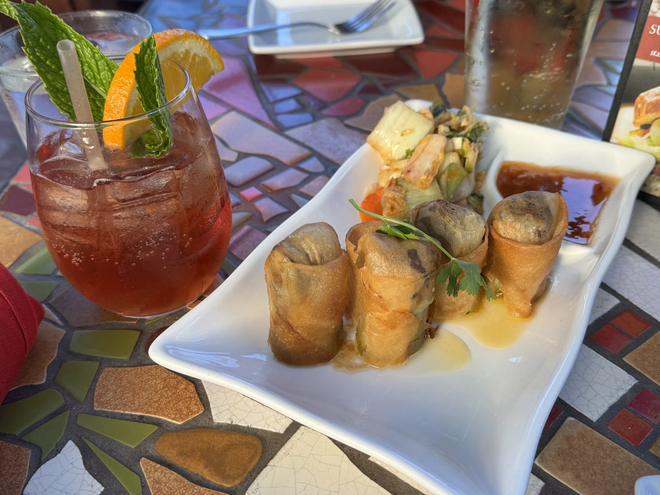 Crispy spring rolls with kimchi slaw, dipping sauce, and a handcrafted cocktail served at Porta Bella restaurant in Carmel-by-the-Sea, California.