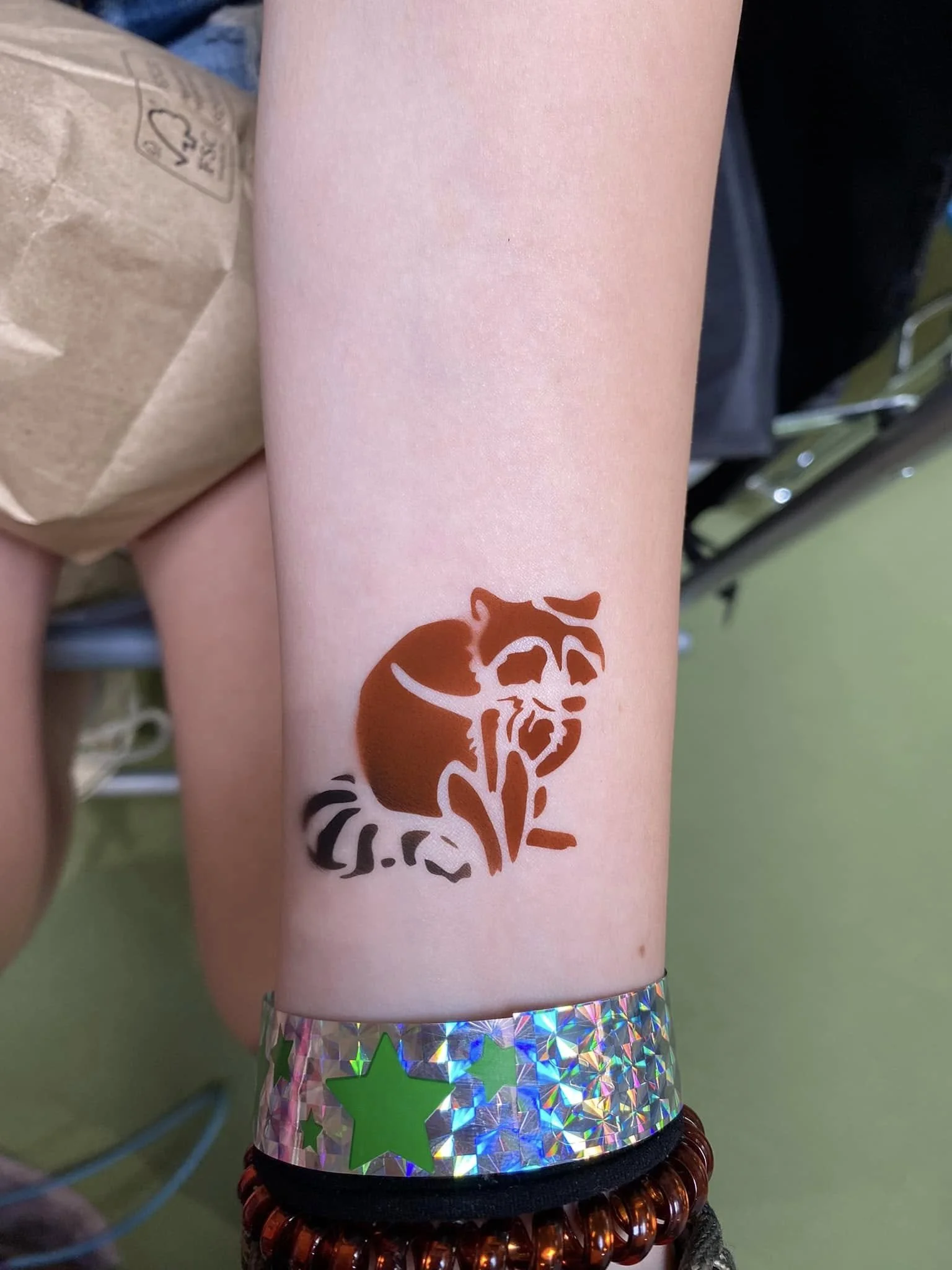 Close-up of a person's forearm with a temporary tattoo featuring racoon. It is a popular design. 