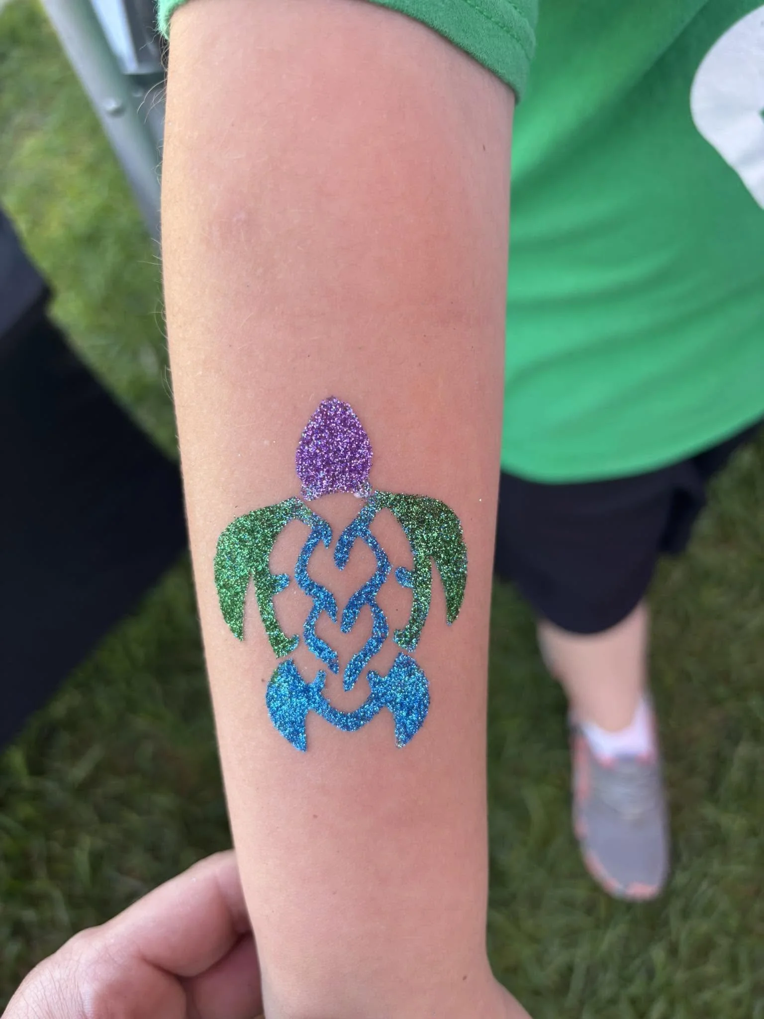 Close-up of a child's forearm with a glittery rainbow-colored turtle.