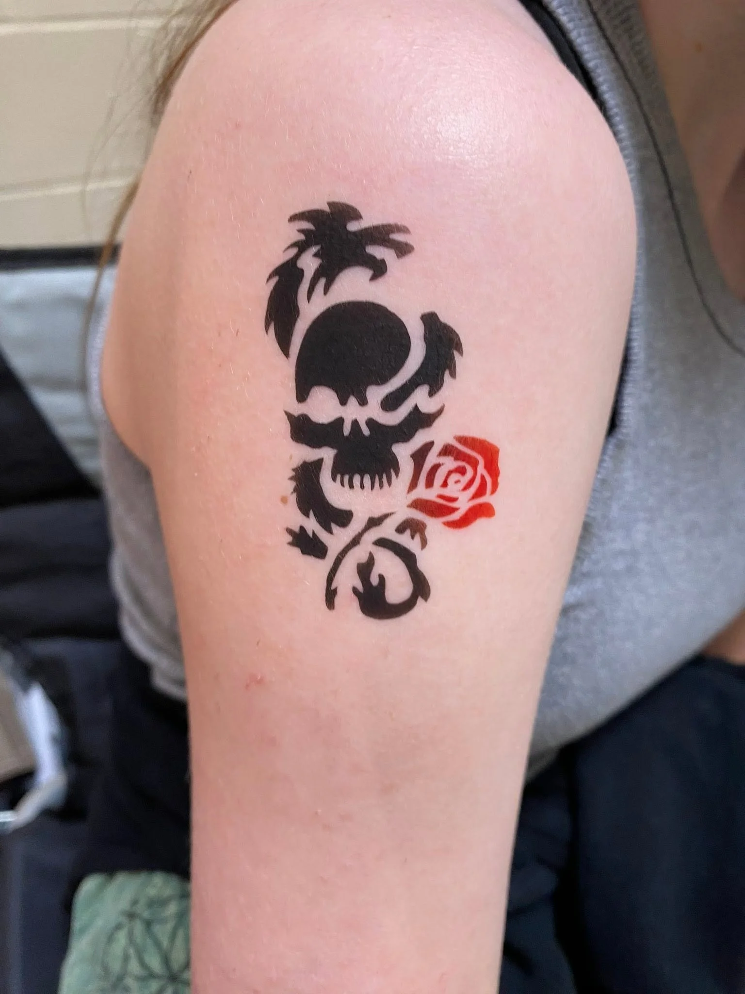 Tattoo of a skull with a rose on the shoulder.