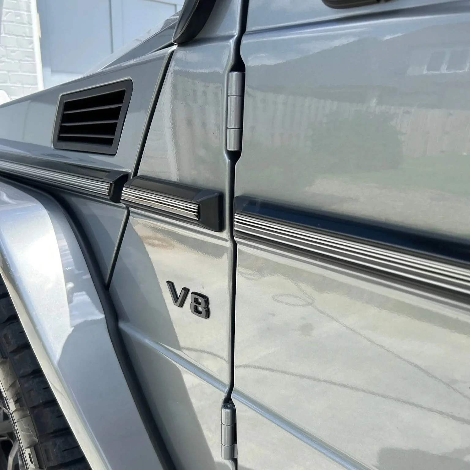 Close-up of the clean exterior and V8 emblem on a silver G-Wagon after being detailed in Rogers Arkansas