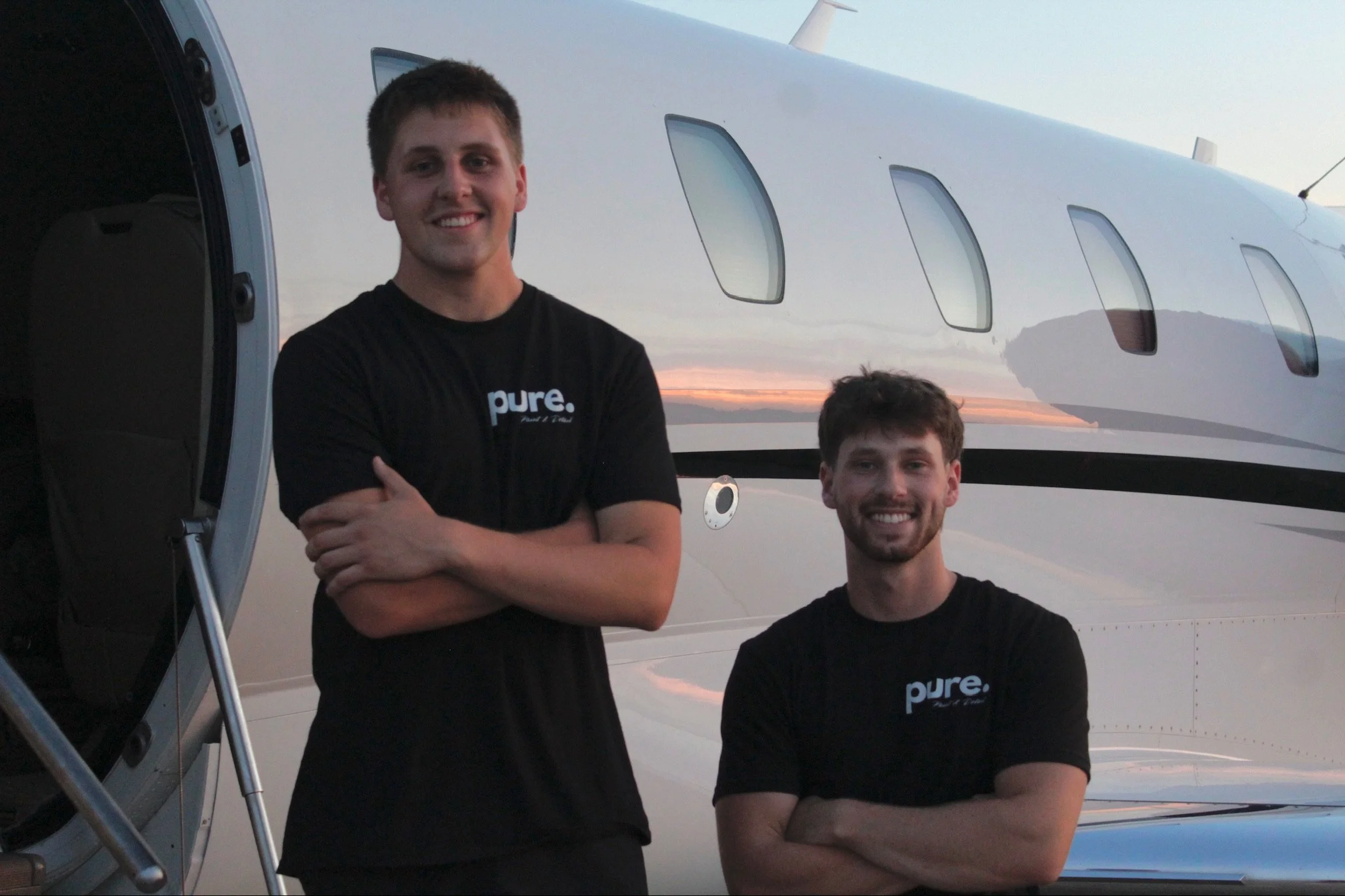 Pure Paint & Detail team members in front of a private jet during aviation detailing work