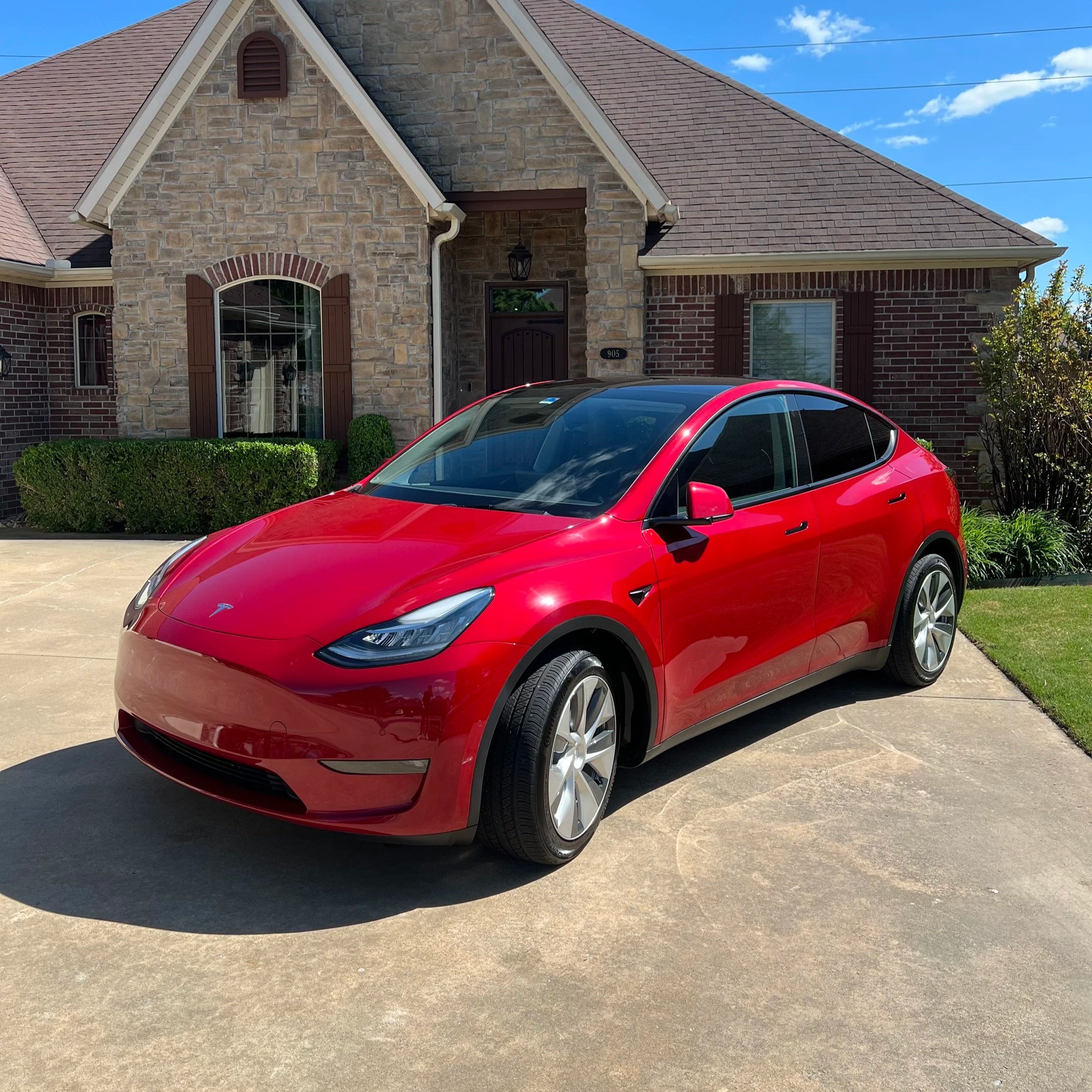 A red Tesla Model Y after being washed with a spray wax sealant applied after a mobile detailing service