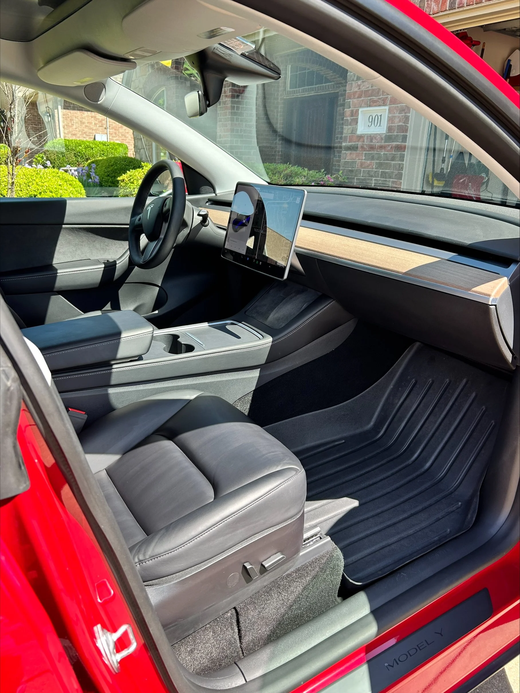 Interior of a Tesla Model Y showing the dashboard, steering wheel, and seat, with a digital display screen in the center.