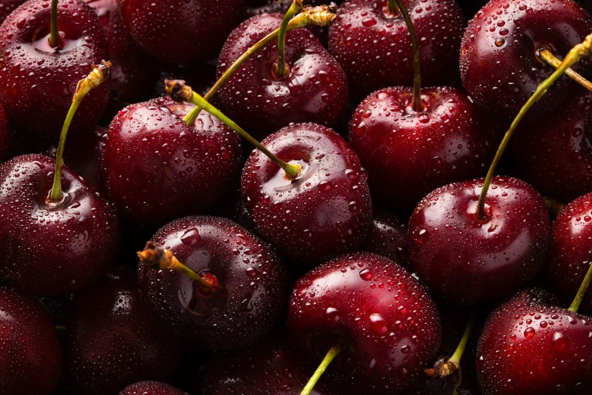 Close-up of fresh, wet cherries with water droplets on a dark background.