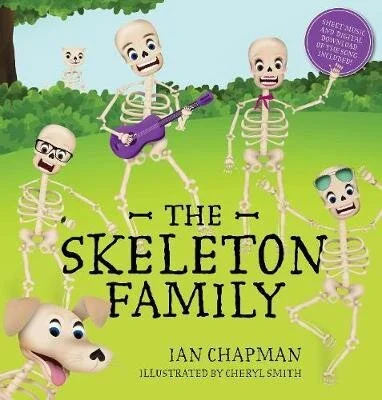 Illustration of five smiling cartoon skeletons and one puppy, with one skeleton playing a purple guitar, in a green outdoor setting with trees and grass. The text reads 'The Skeleton Family' by Ian Chapman, illustrated by Cheryl Smith.
