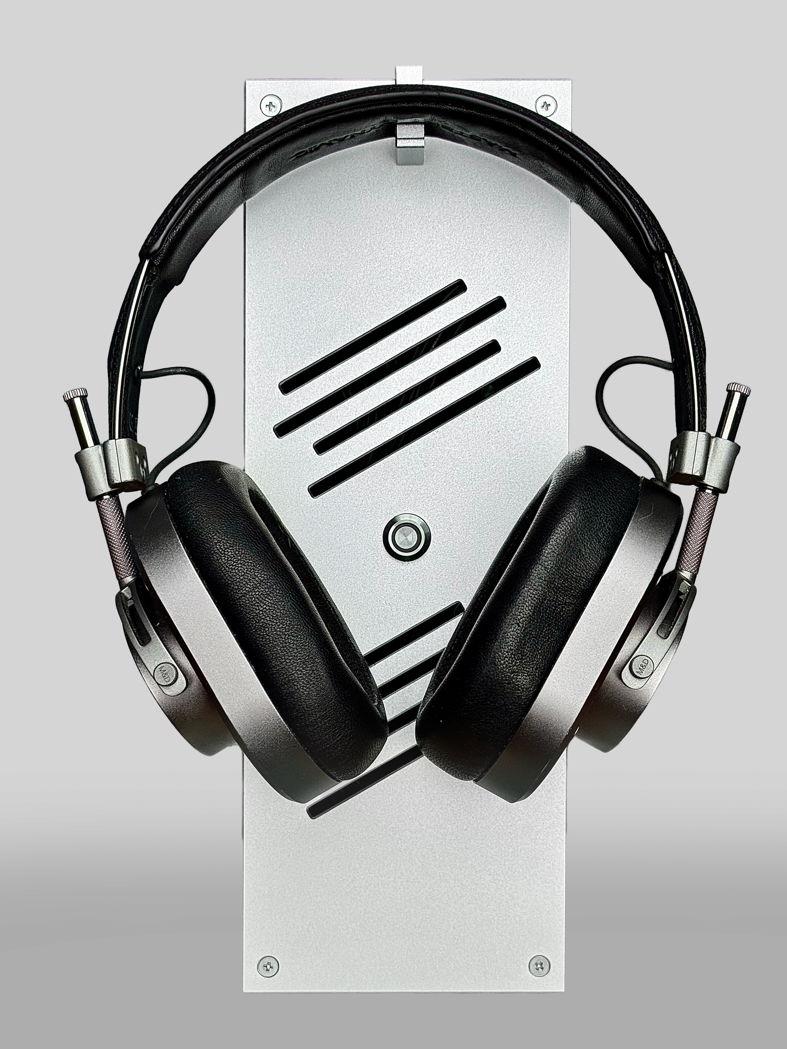 Black over-ear headphones hanging on a wall mounted a silver panel.