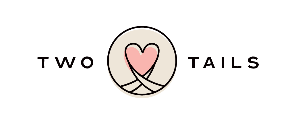 Logo with two stylized tails forming a heart shape inside a circle, with the words "TWO TAILS" on either side.