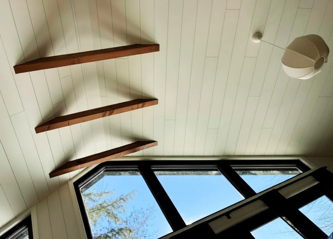 Vaulted shiplap ceiling with floating walnut shelves and large windows, interior design by MODO Design Lab New England