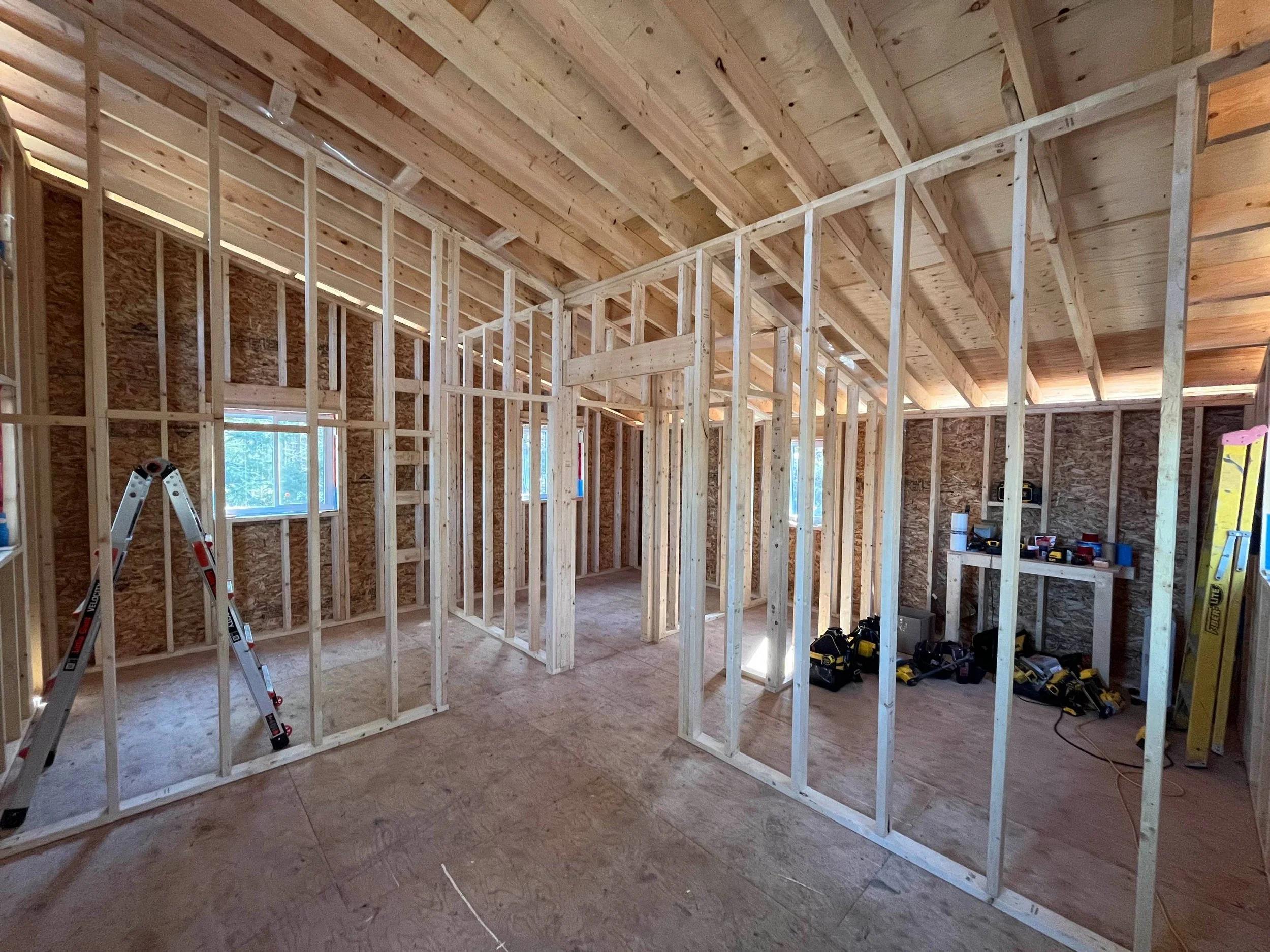 Interior of a house under construction with wooden framing and tools.
